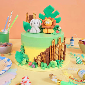 Jungle Cake with handmade lion and elephant toppers, edible foliage, and chocolate tree trunks by Crumbs & Doilies.